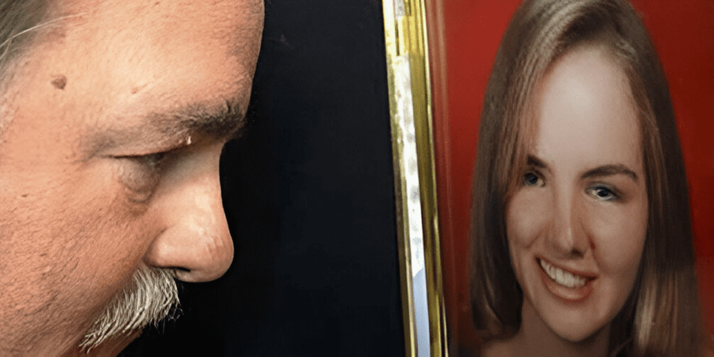 Man looking at framed portrait of woman.